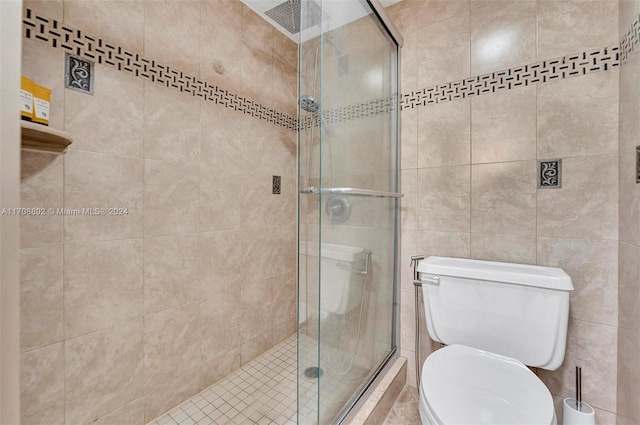 bathroom featuring toilet, an enclosed shower, and tile walls