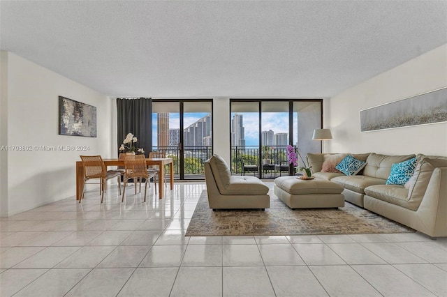 living room featuring light tile patterned flooring, a wall of windows, and a textured ceiling