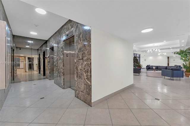 hallway featuring light tile patterned flooring, tile walls, and elevator