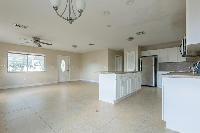 kitchen featuring a center island, white cabinets, ceiling fan with notable chandelier, decorative light fixtures, and stainless steel appliances