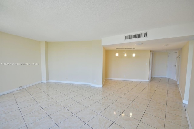 tiled spare room featuring a textured ceiling