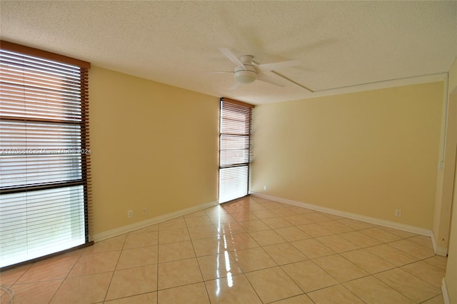 spare room with ceiling fan, light tile patterned flooring, and a textured ceiling