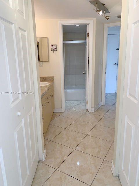 bathroom with tile patterned floors, ceiling fan, vanity, and tiled shower / bath