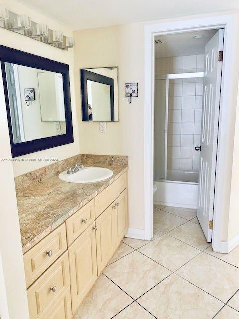 bathroom featuring tile patterned floors, vanity, and bath / shower combo with glass door