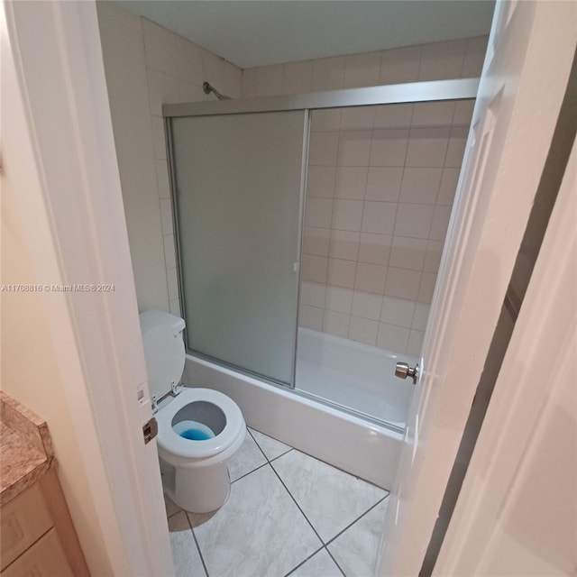 bathroom featuring shower / bath combination with glass door, tile patterned flooring, and toilet