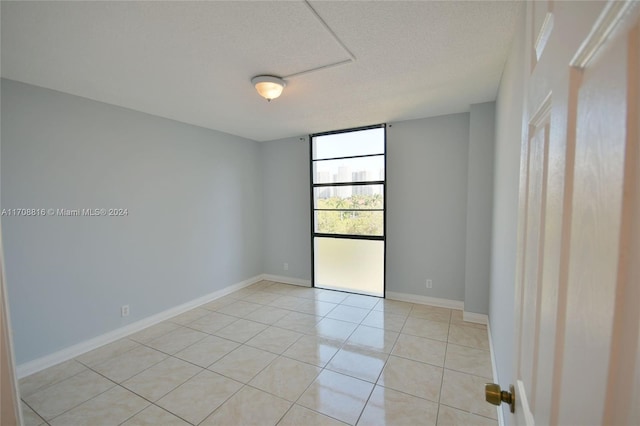 tiled empty room featuring a textured ceiling