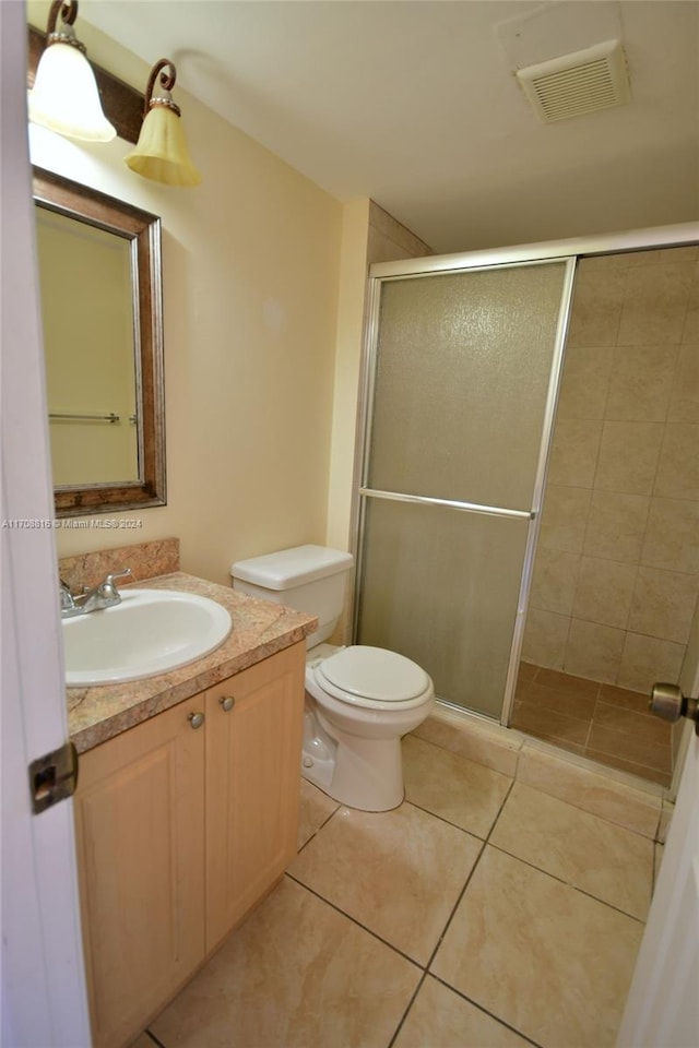 bathroom with tile patterned floors, vanity, an enclosed shower, and toilet