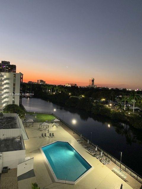 pool at dusk with a patio and a water view