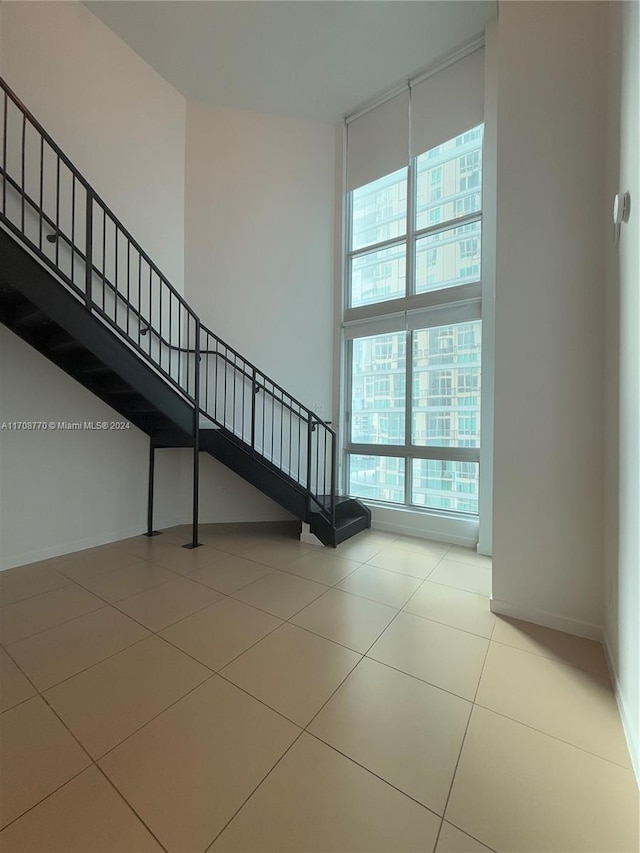 staircase featuring tile patterned flooring and a high ceiling