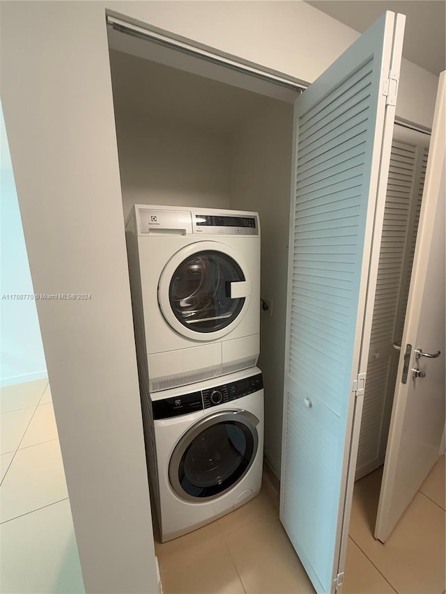 washroom with light tile patterned floors and stacked washer / dryer