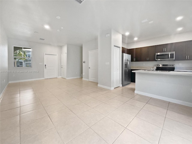 kitchen featuring dark brown cabinets, light tile patterned floors, and stainless steel appliances