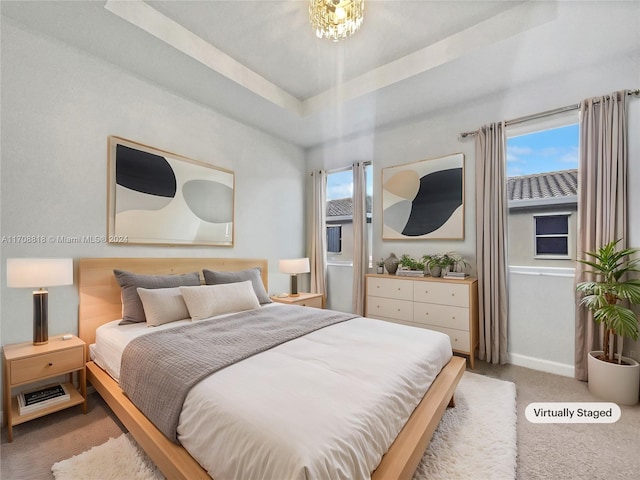 carpeted bedroom with a raised ceiling and multiple windows