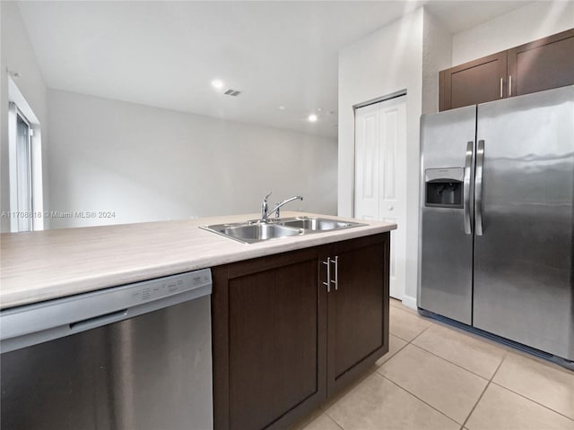 kitchen featuring appliances with stainless steel finishes, light tile patterned floors, dark brown cabinets, and sink