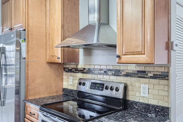 kitchen with dark stone countertops, wall chimney range hood, backsplash, and appliances with stainless steel finishes