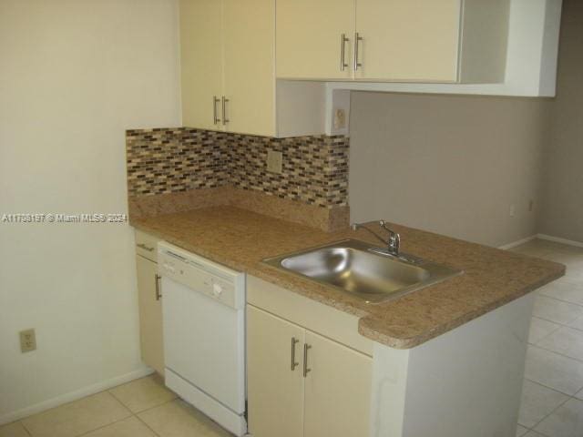 kitchen featuring kitchen peninsula, backsplash, white dishwasher, sink, and light tile patterned floors