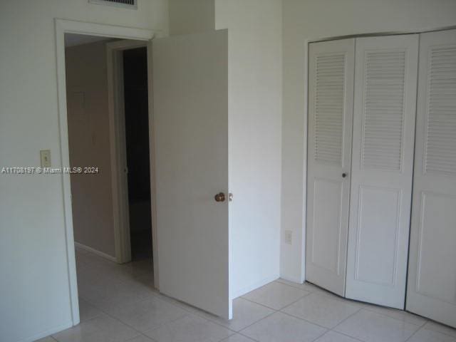 unfurnished bedroom featuring light tile patterned floors and a closet