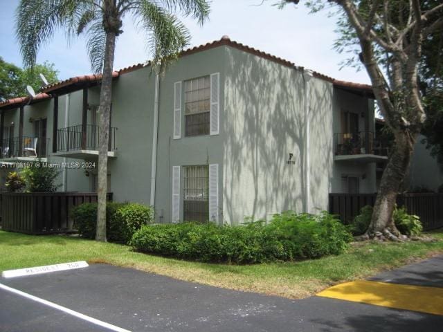 10776 N Kendall Dr Unit F-16, Miami, FL 33176 - view of home's exterior featuring stucco siding, a balcony, uncovered parking, and a tile roof