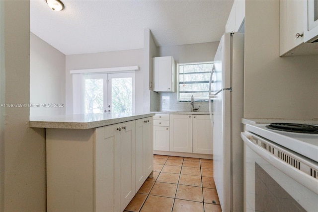 kitchen featuring white cabinets, white appliances, sink, and light tile patterned floors