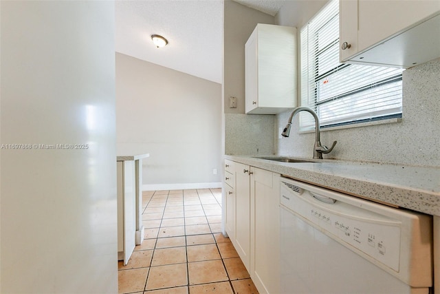 kitchen with white dishwasher, sink, tasteful backsplash, light tile patterned flooring, and white cabinetry