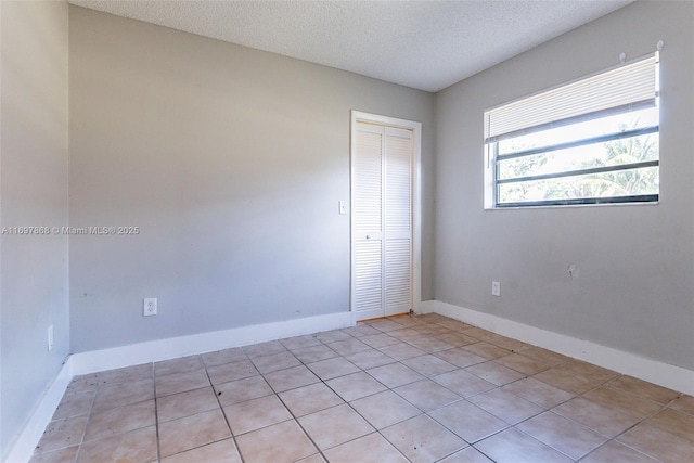 unfurnished room featuring light tile patterned floors and a textured ceiling