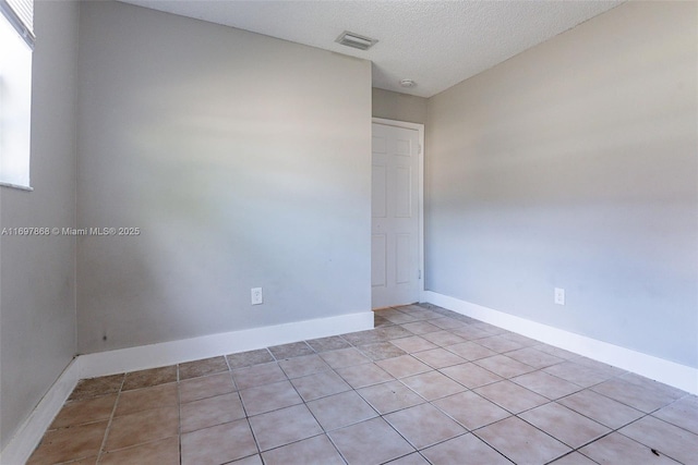 empty room featuring light tile patterned floors and a textured ceiling