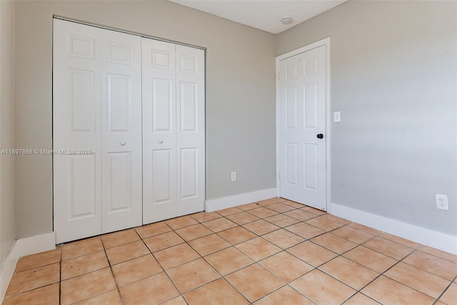 unfurnished bedroom with a closet and light tile patterned floors