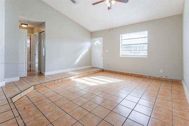 tiled empty room with a textured ceiling, ceiling fan, and lofted ceiling