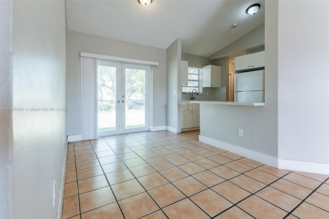 kitchen with white cabinetry, french doors, sink, white fridge, and lofted ceiling