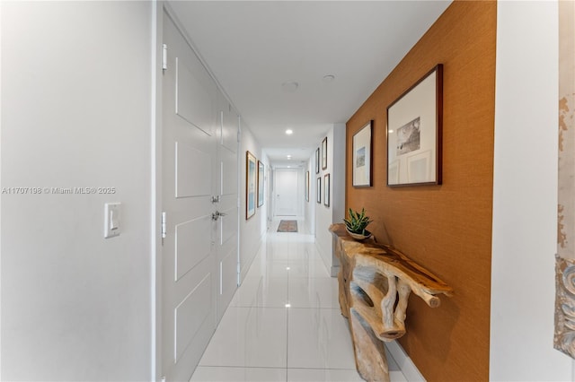 corridor featuring light tile patterned floors, baseboards, an accent wall, and recessed lighting