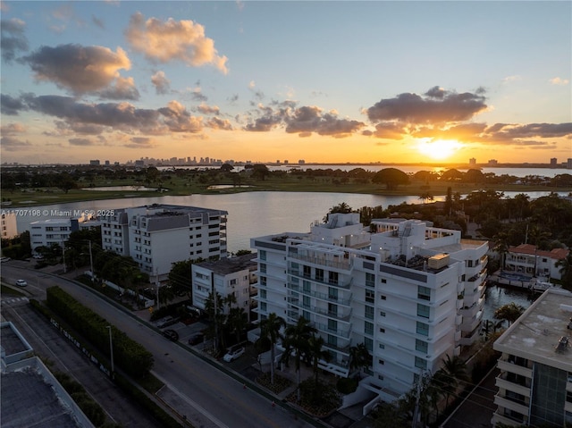 aerial view at dusk featuring a water view and a city view