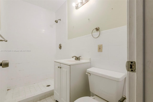 bathroom featuring a tile shower, tile patterned floors, toilet, vanity, and tile walls