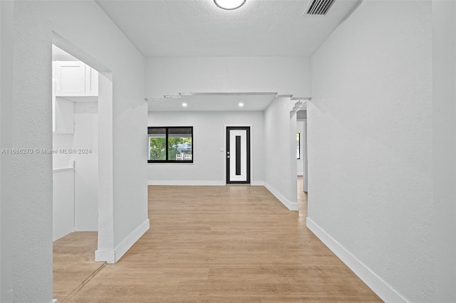 hall with a textured ceiling and light hardwood / wood-style flooring