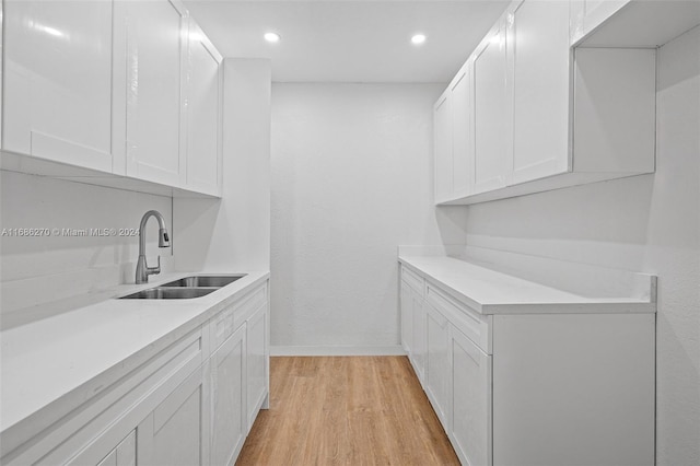 kitchen with sink, white cabinets, and light hardwood / wood-style flooring