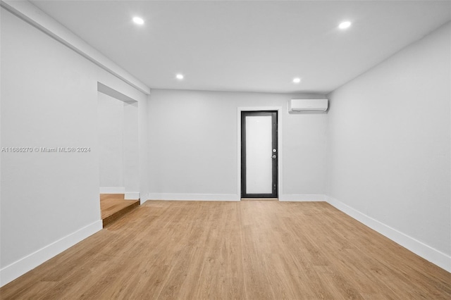 unfurnished room featuring light hardwood / wood-style floors and a wall unit AC