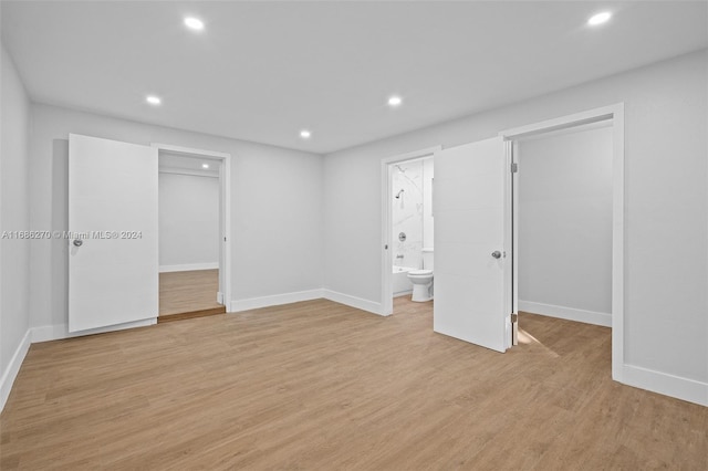 unfurnished bedroom with ensuite bathroom and light hardwood / wood-style flooring