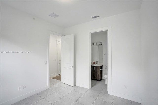 unfurnished bedroom featuring ensuite bathroom and light tile patterned floors