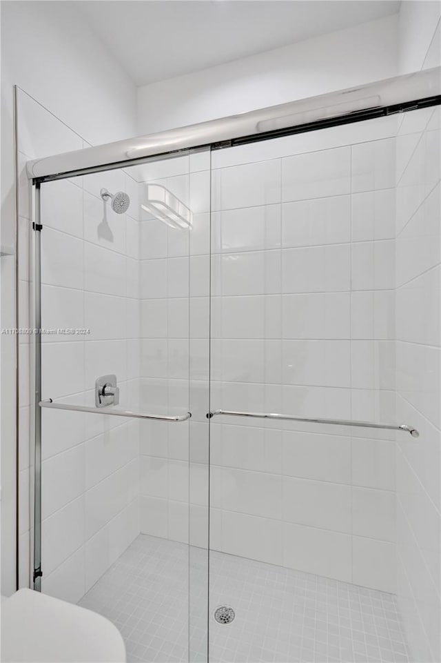 bathroom with a shower with door and toilet