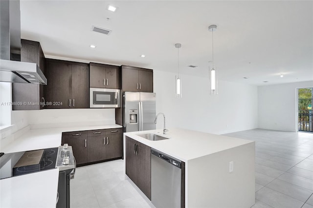 kitchen featuring sink, hanging light fixtures, wall chimney range hood, an island with sink, and appliances with stainless steel finishes