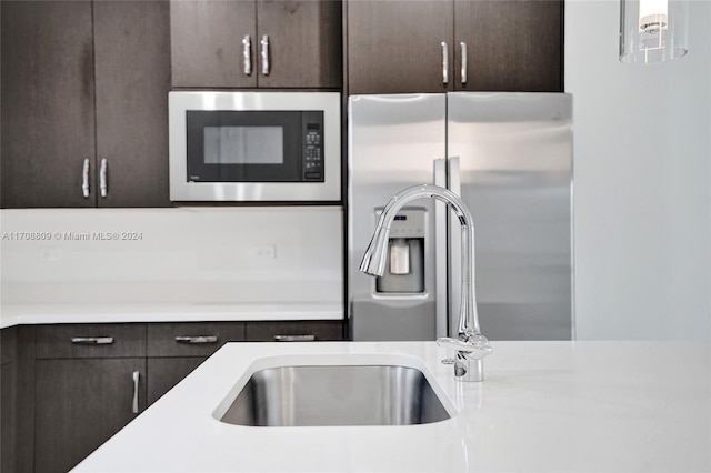 kitchen with dark brown cabinetry, hanging light fixtures, and stainless steel appliances