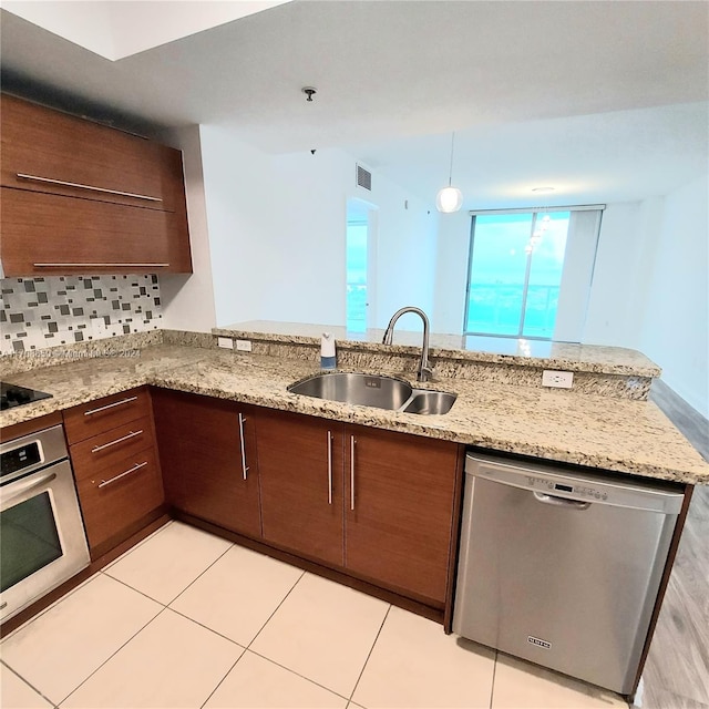 kitchen featuring light stone countertops, sink, stainless steel appliances, tasteful backsplash, and kitchen peninsula