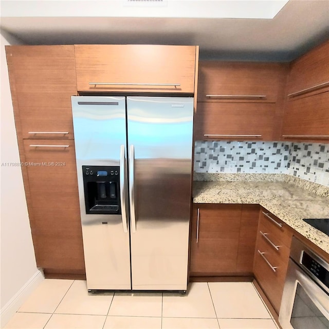 kitchen featuring light stone countertops, appliances with stainless steel finishes, tasteful backsplash, and light tile patterned floors