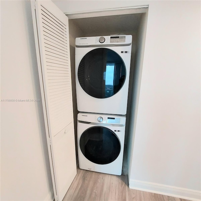 laundry room featuring stacked washer / dryer and light wood-type flooring