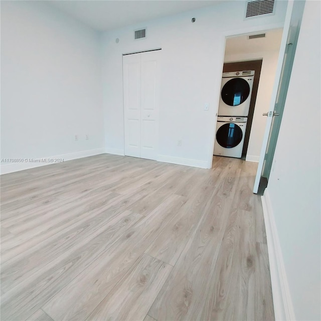 empty room featuring light hardwood / wood-style floors and stacked washer and clothes dryer