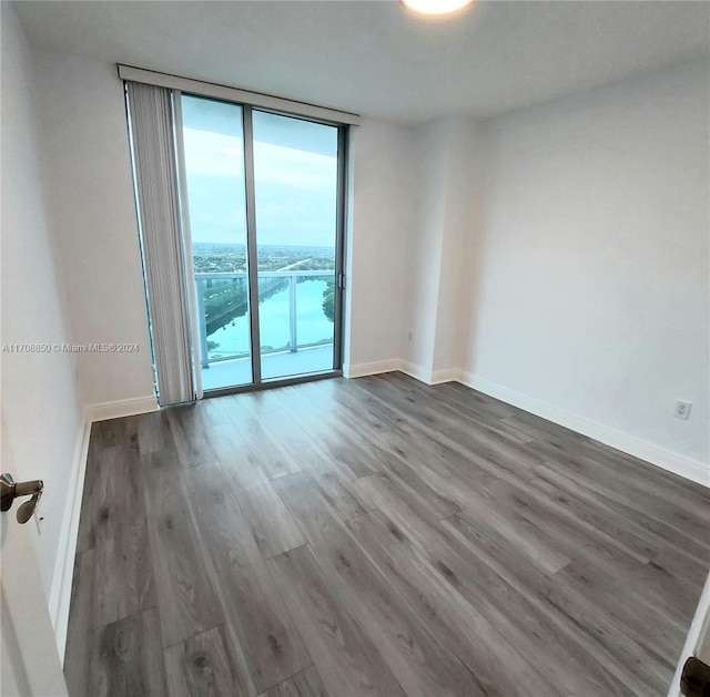 empty room featuring floor to ceiling windows and dark hardwood / wood-style floors