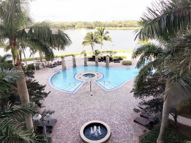 view of swimming pool featuring a community hot tub, a water view, and a patio area