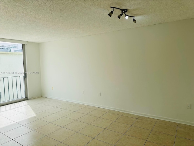 tiled spare room featuring rail lighting and a textured ceiling