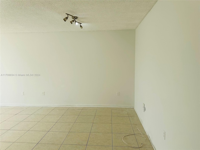 spare room featuring light tile patterned floors and a textured ceiling