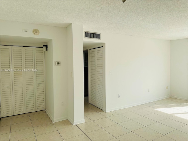 unfurnished bedroom featuring light tile patterned floors, a textured ceiling, and a closet