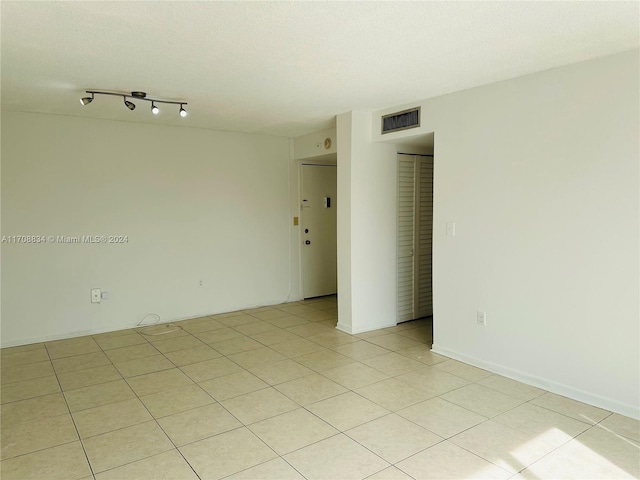 empty room with light tile patterned floors and a textured ceiling