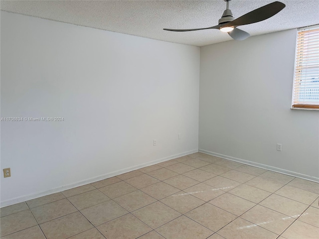 tiled empty room featuring ceiling fan and a textured ceiling